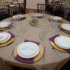 Table set up on a round table with vintage mixed china and gold chargers and glassware.