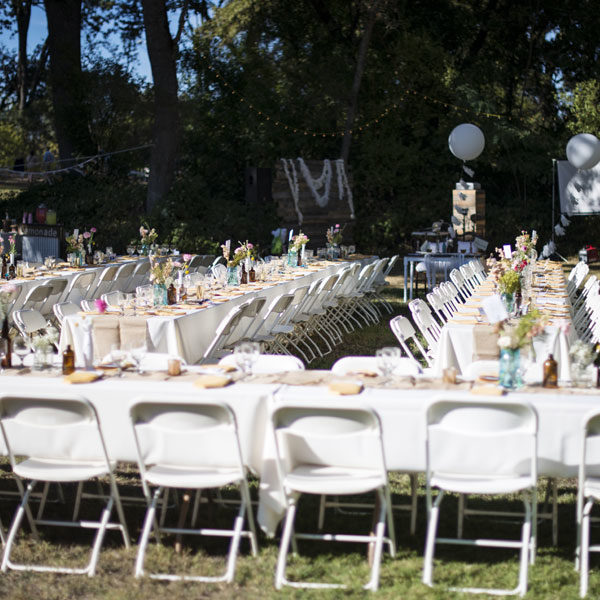 Basic white folding chairs with banquet tables in an outdoor setting event
