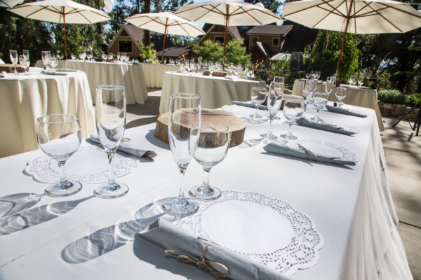 Umbrella tables, glassware and flatware at outdoor reception