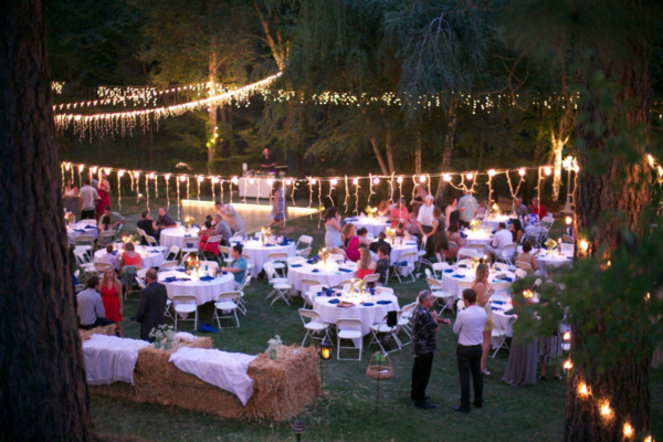 Dinner reception - round folding tables, chair rental, and market light strands set the scene