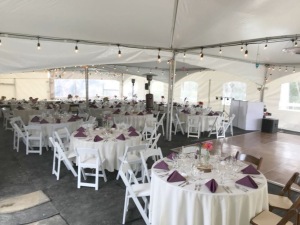 White resin chairs, round folding tables with market strand lighting.