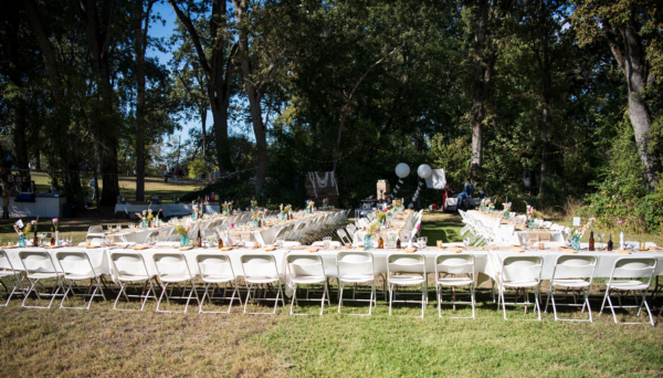 Outdoor reception with basic white chairs and 8ft tables